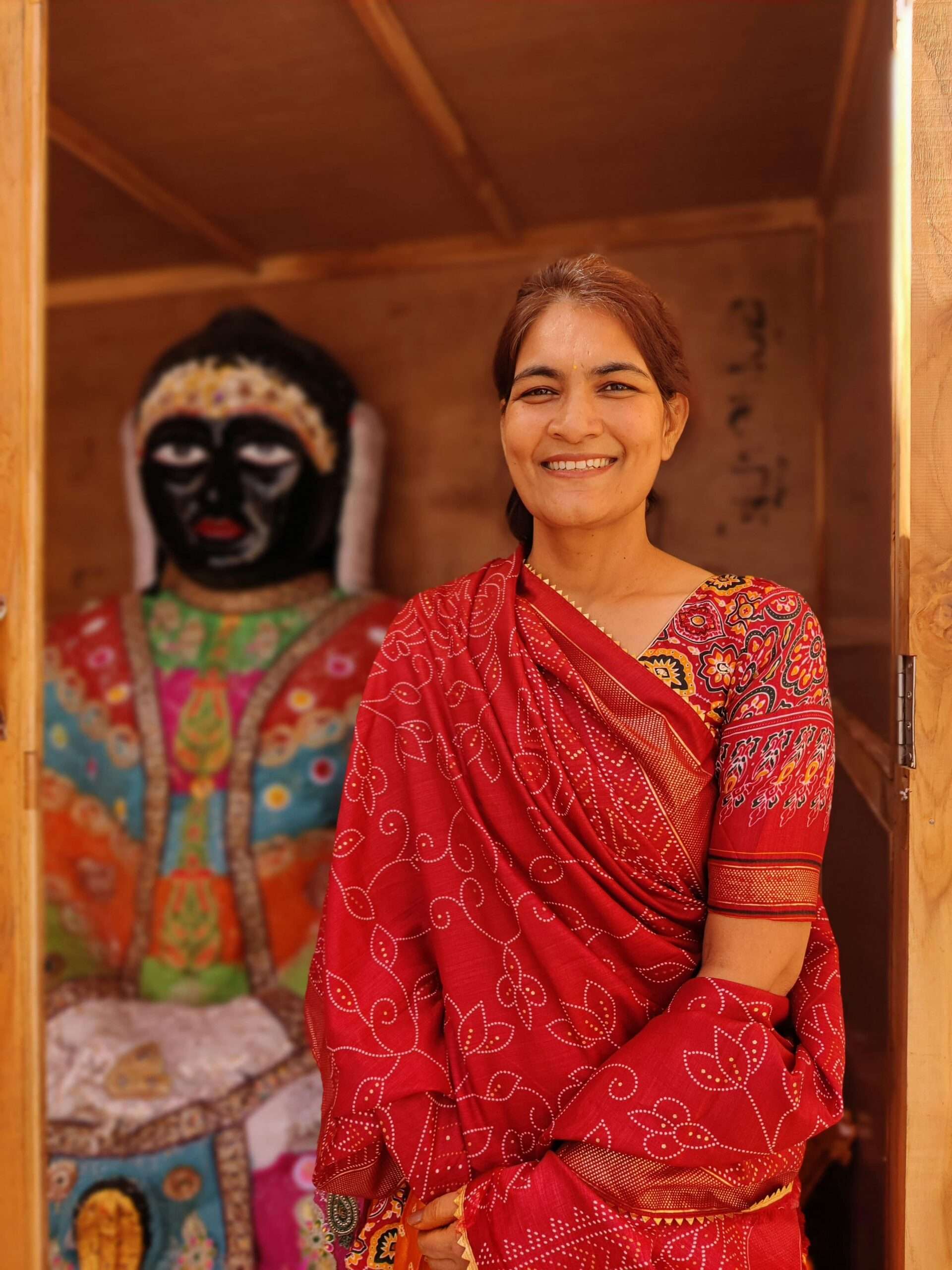 Smiling Indian woman in vibrant red sari with colorful artwork in Jodhpur, Rajasthan.